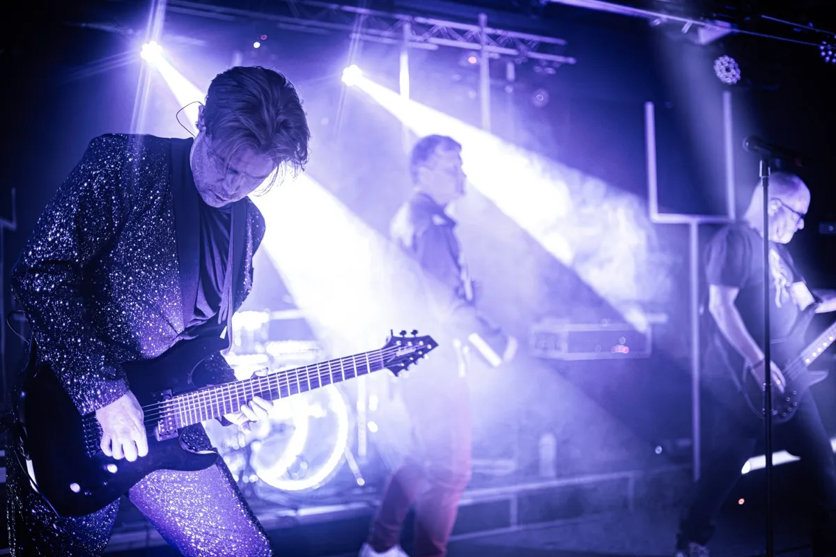 Guitarist leaning into riff with purple stage lighting