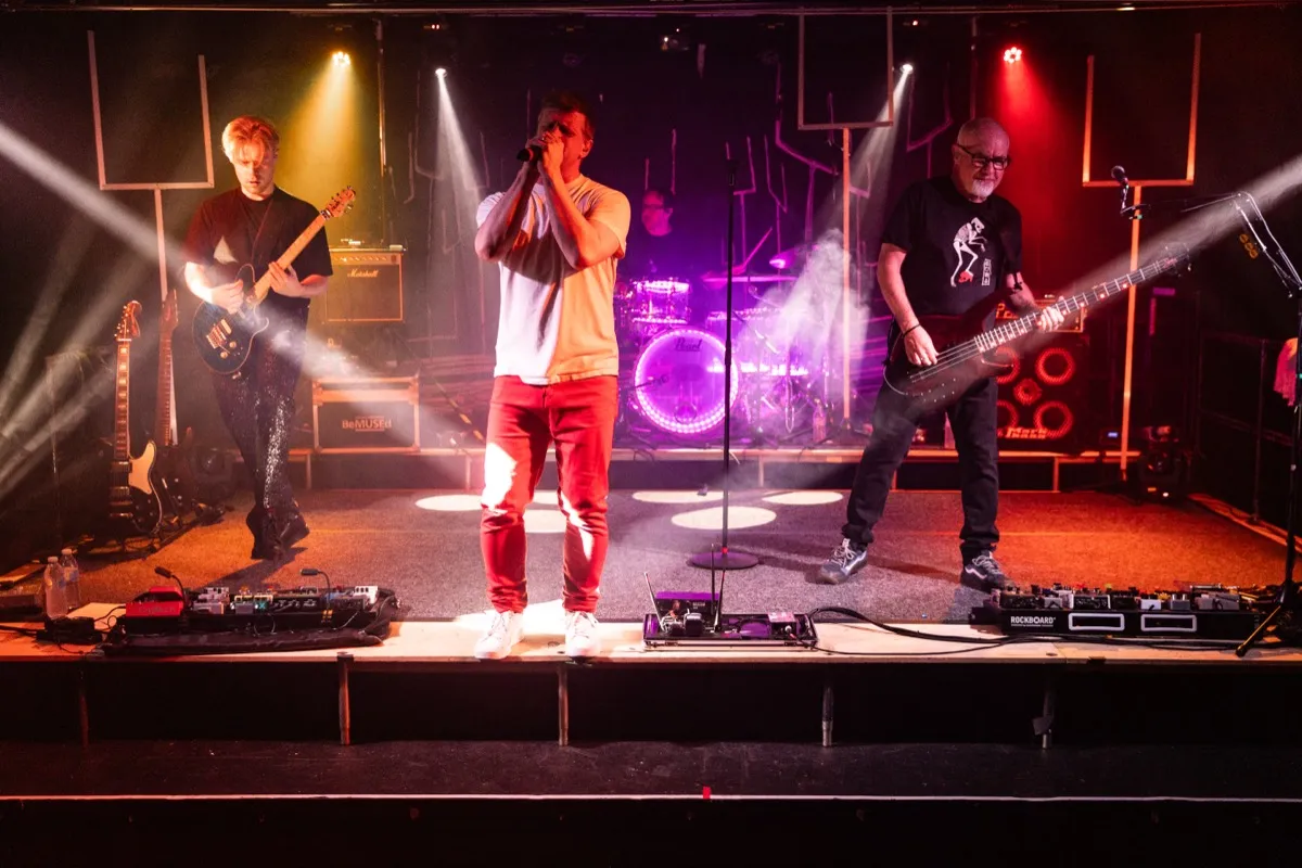 Full band on stage with warm multi-colour lighting and smoke